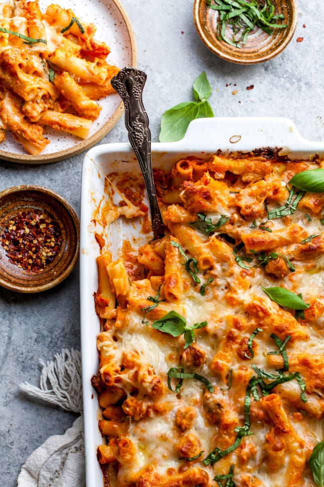 Baked Ziti in white baking dish with serving spoon. 
