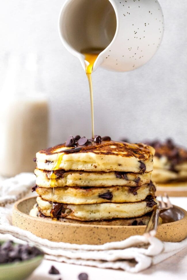 stack of Chocolate Chip Pancakes with maple syrup being poured over the top