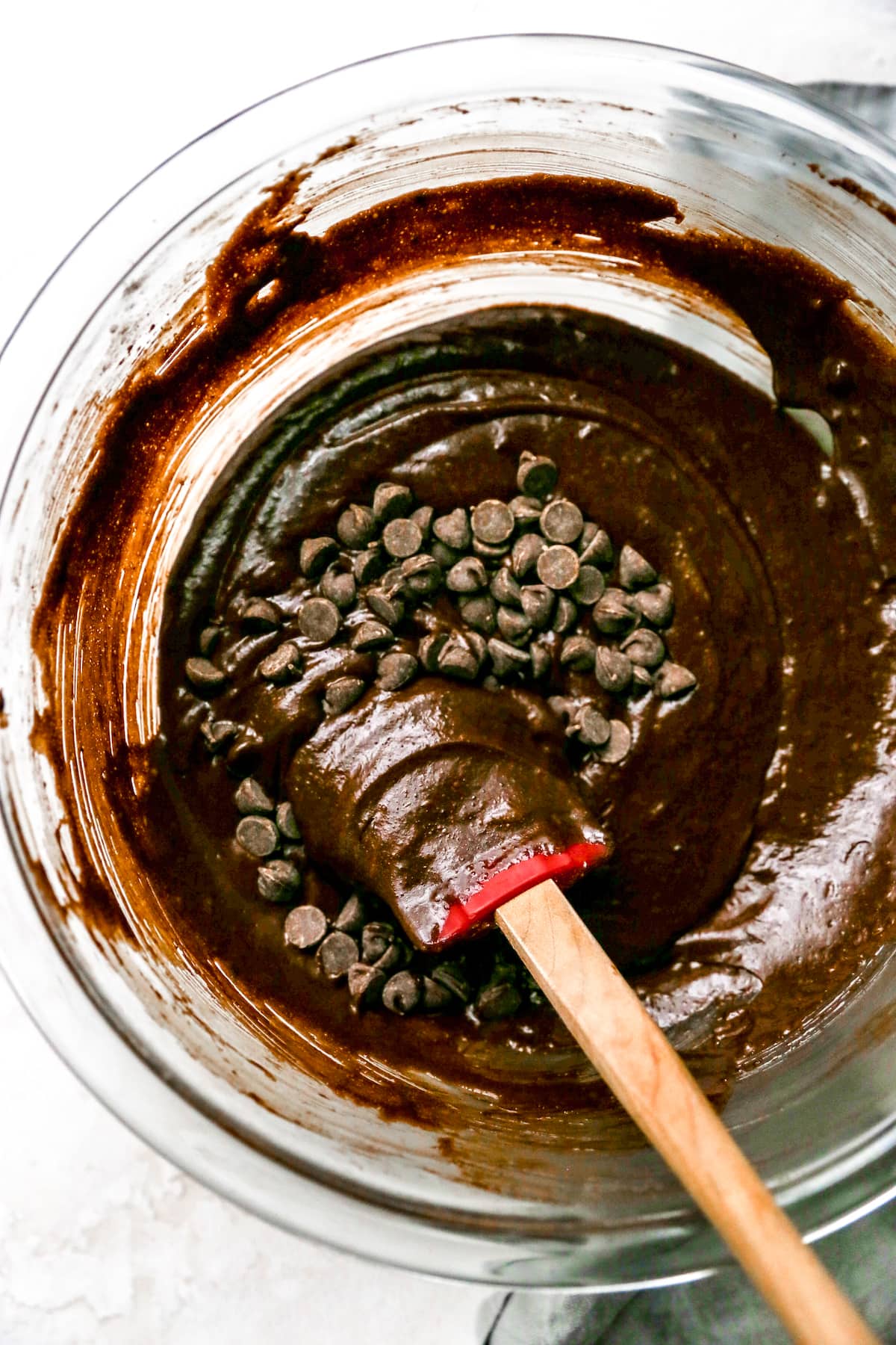 Gluten Free brownie batter in bowl with chocolate chips and spatula. 
