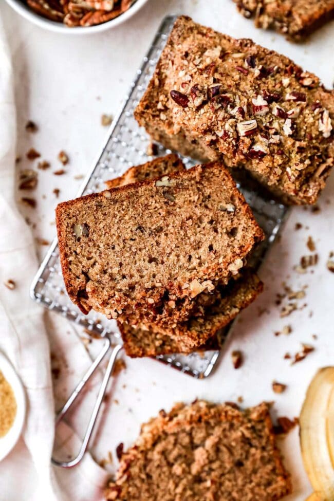 Banana Nut Bread loaf cut into slices and stacked on cooling rack. 