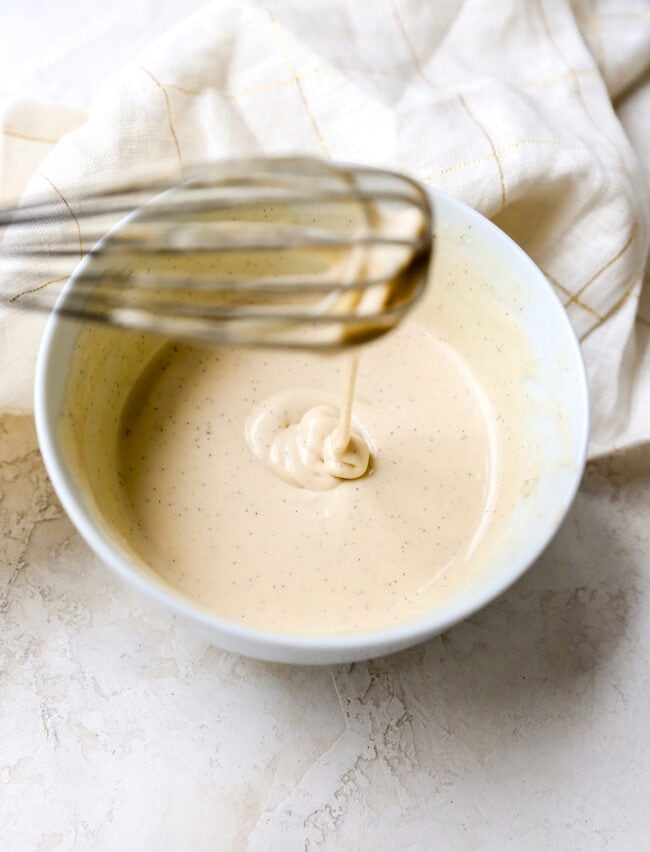 Cream cheese glaze in a bowl with a whisk for carrot cake baked oatmeal