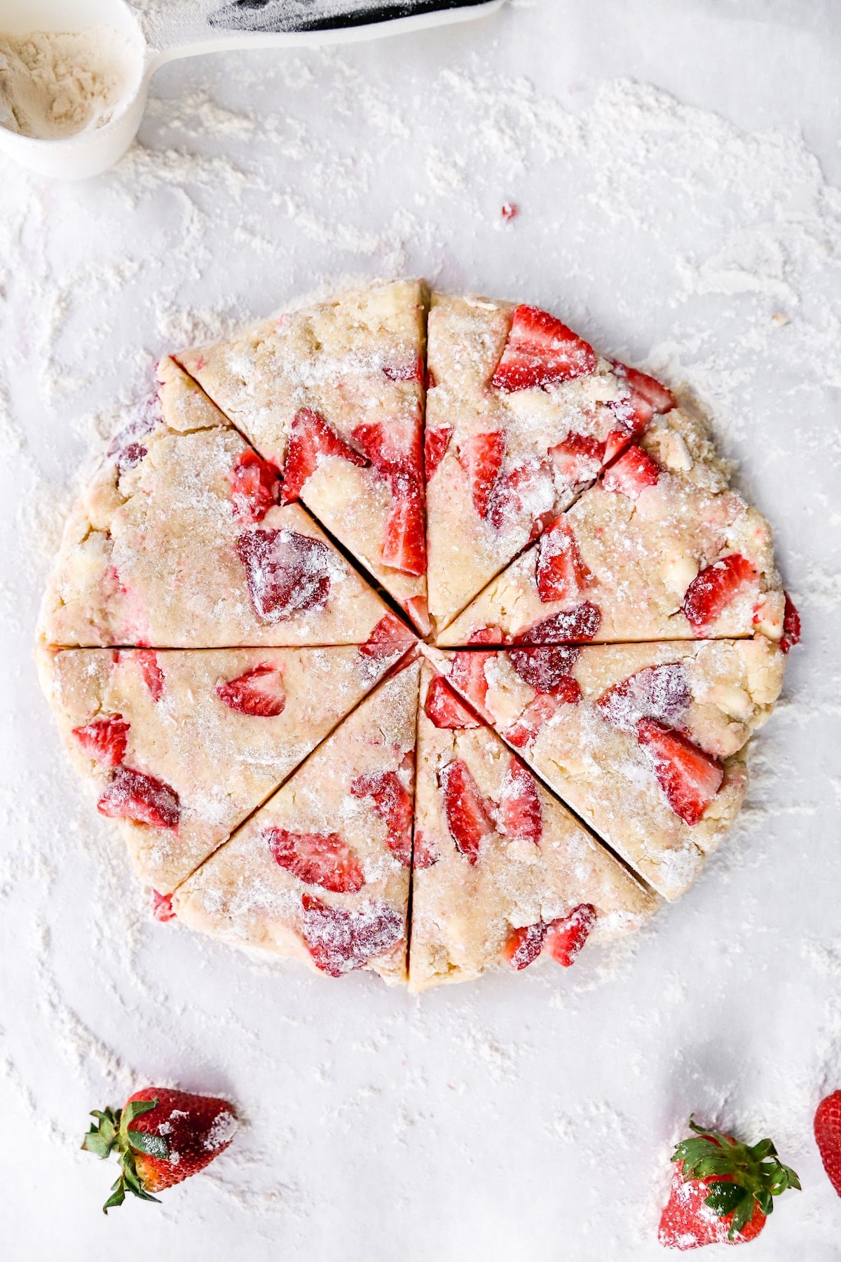 strawberry scone dough cut into triangles on floured surface.
