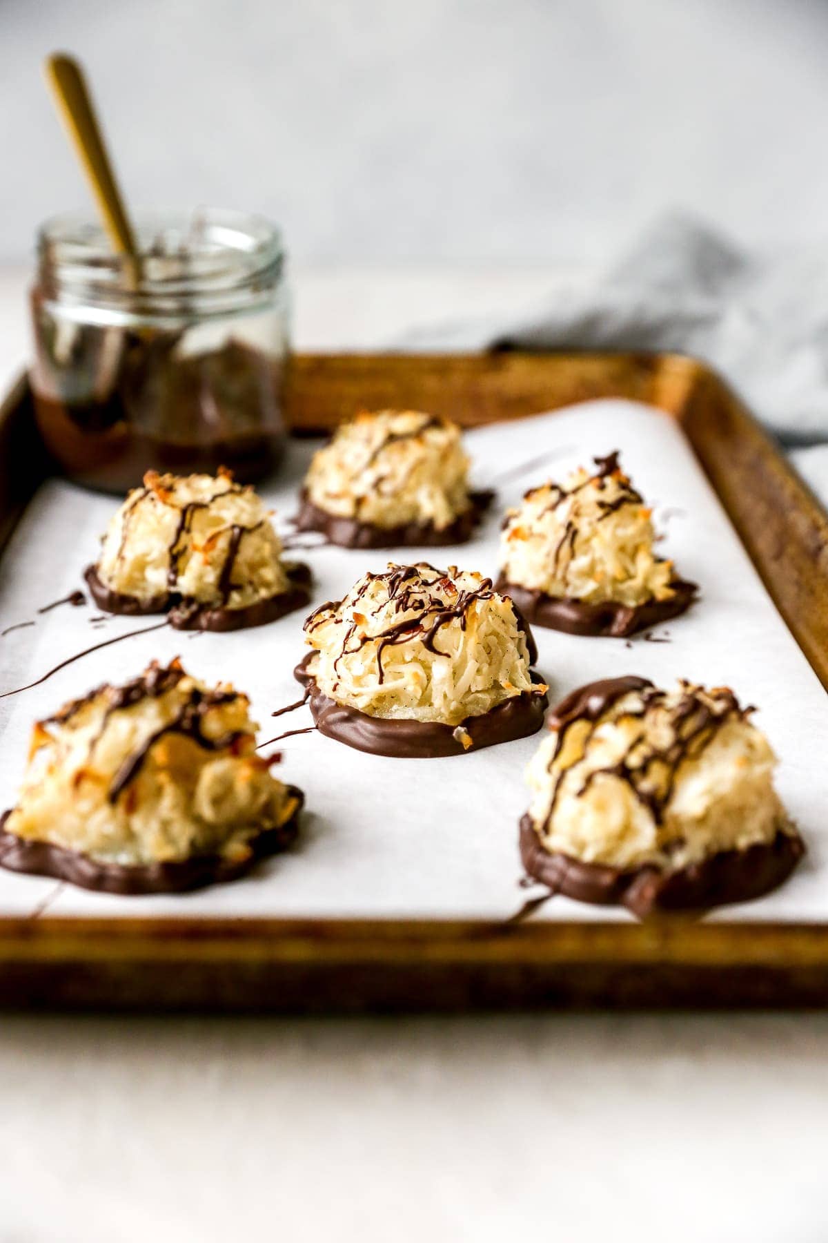 Coconut Macaroons dipped in chocolate on baking sheet with parchment paper. 