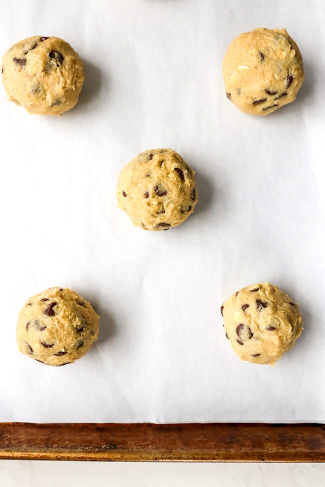 Doubletree Cookie dough balls on baking sheet with parchment paper ready to be baked. 