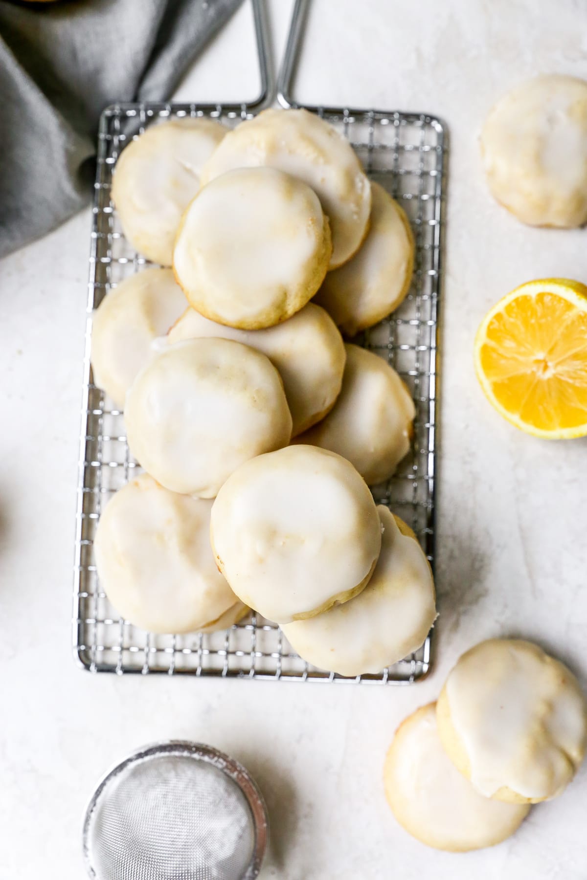 glazed lemon cookies stacked on cooling rack.