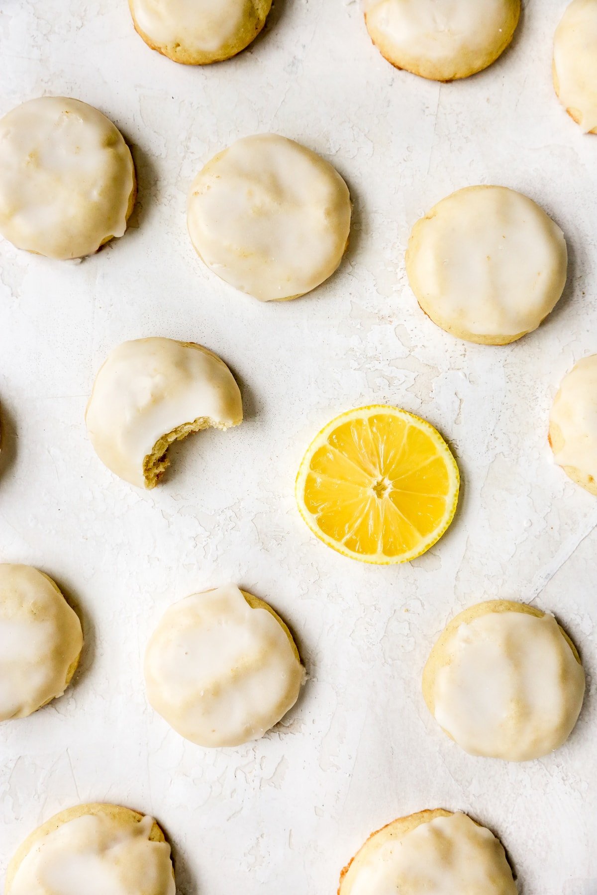 glazed lemon cookies on counter with lemon slice. 