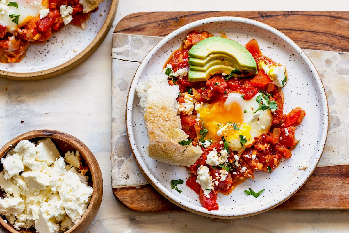 shakshuka on plates with feta cheese and crusty bread. 