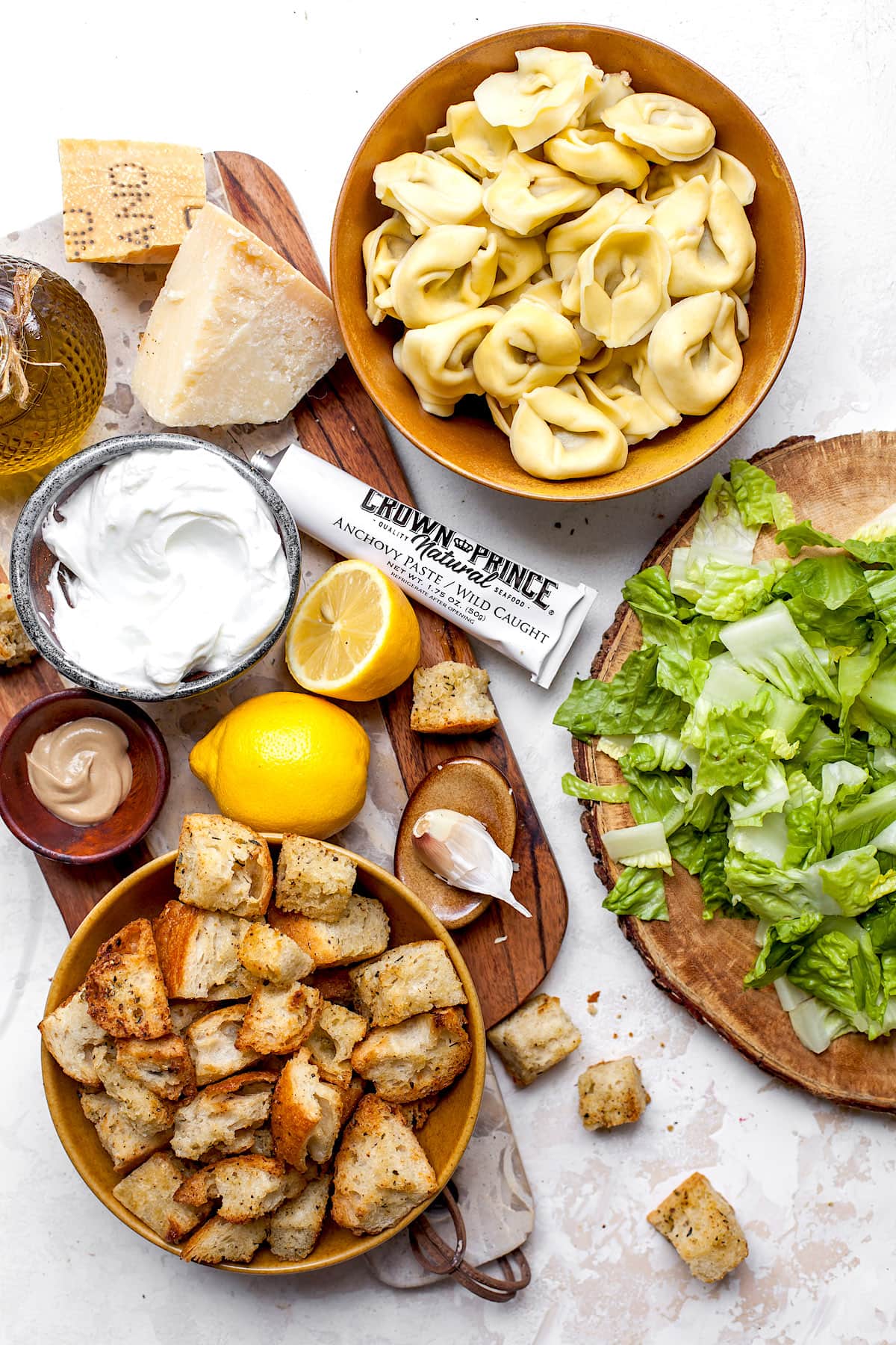 Tortellini Caesar Salad Ingredients  in bowls on wood board. 