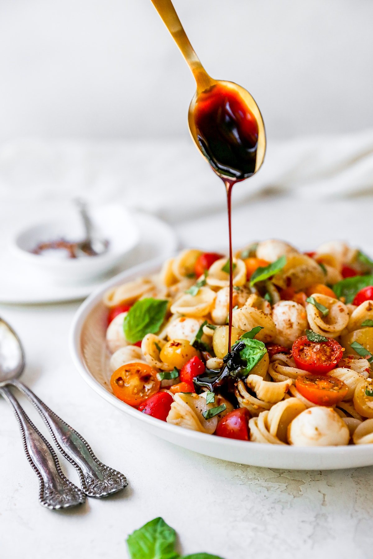 caprese pasta salad in bowl with balsamic glaze.