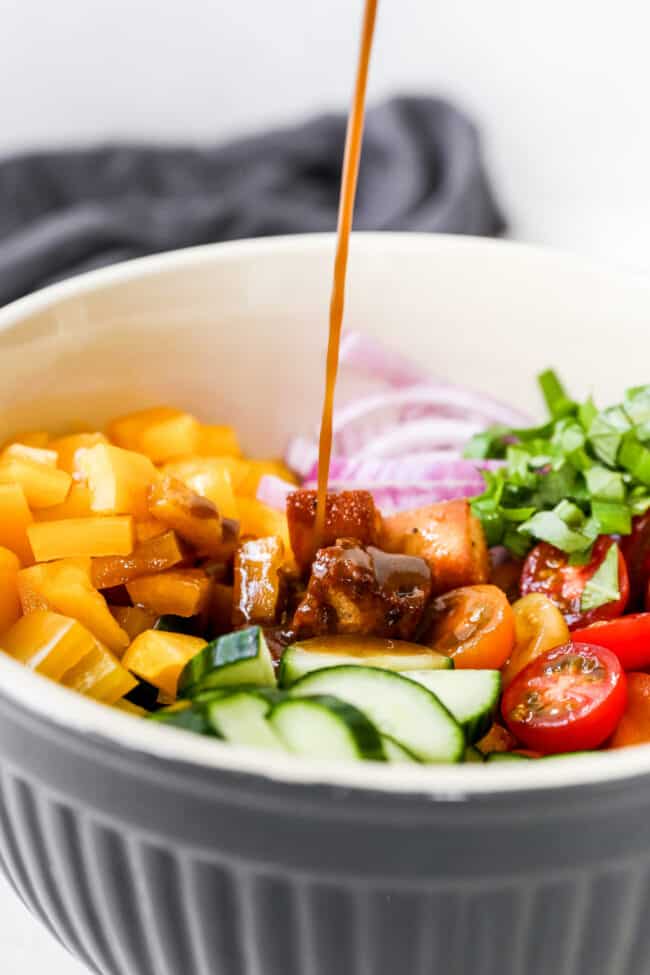 Balsamic vinaigrette pouring over Panzanella Salad