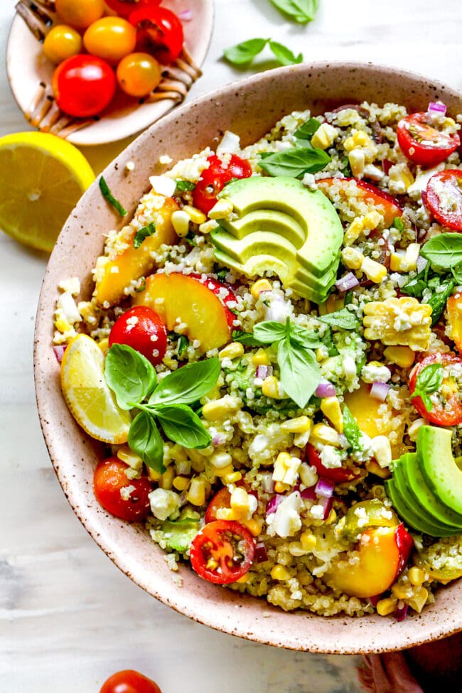 summer quinoa salad in bowl with avocado slices and fresh basil