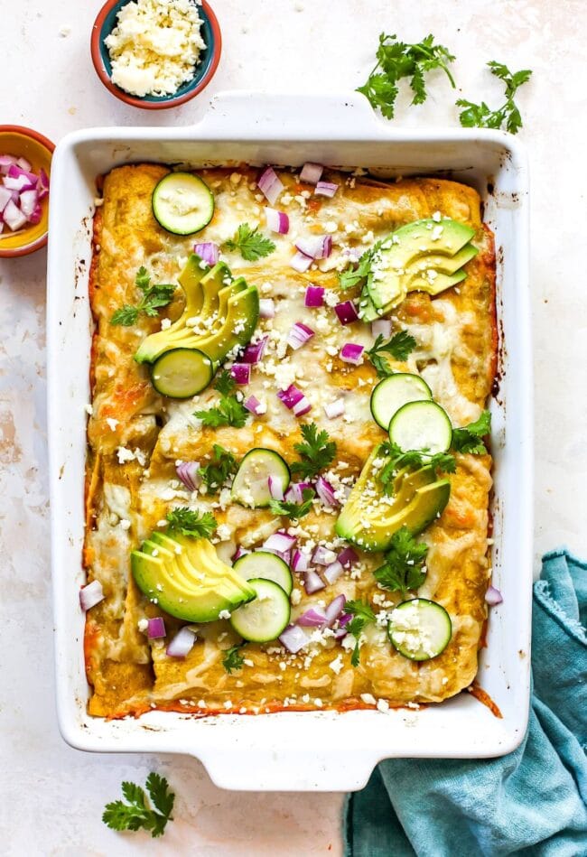 corn and zucchini enchiladas in pan with toppings