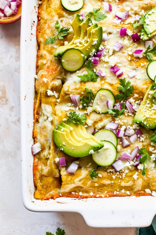 baked corn and zucchini enchiladas in pan with melted cheese and toppings