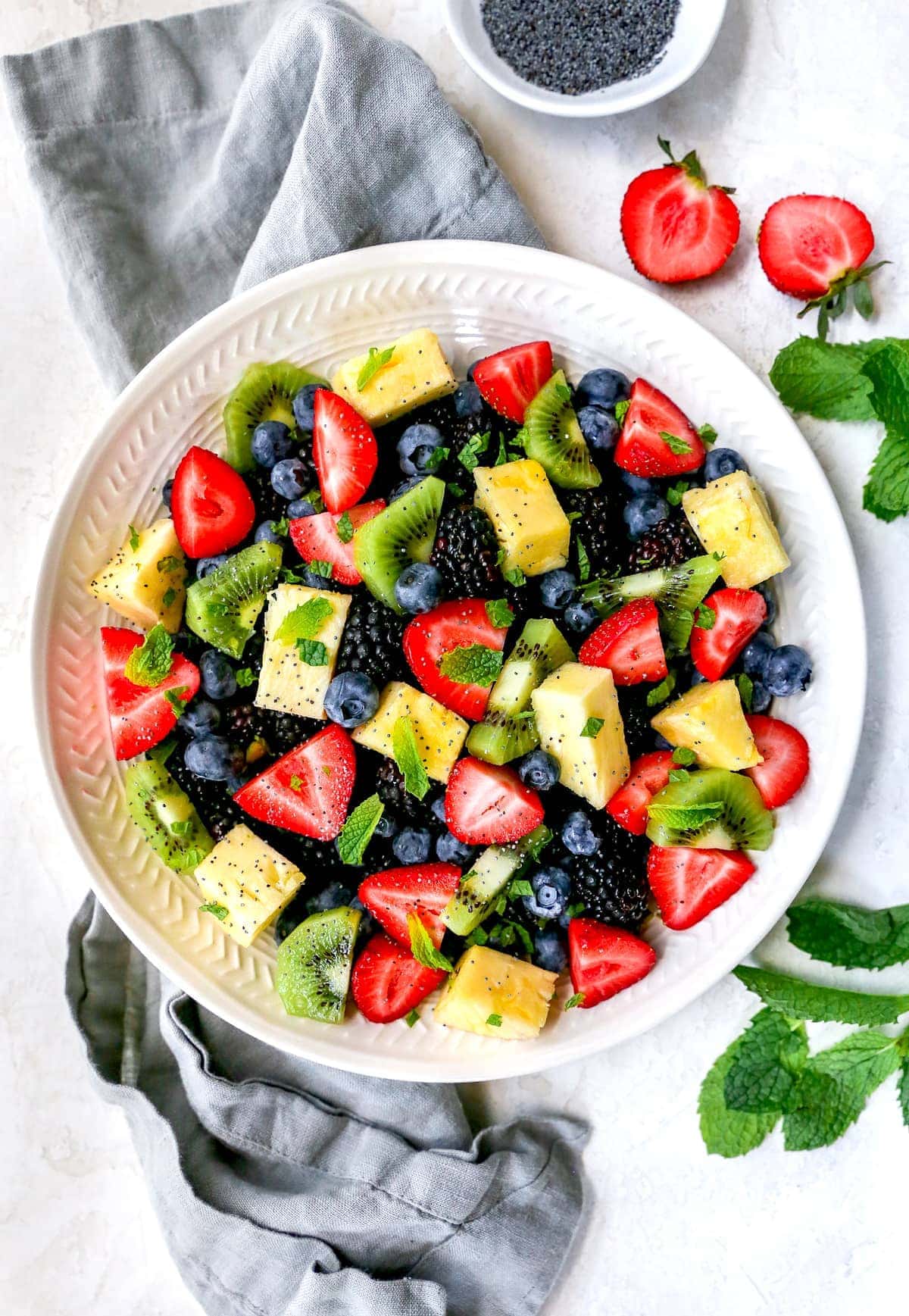 Fruit salad in bowl with citrus poppy seed dressing and mint.