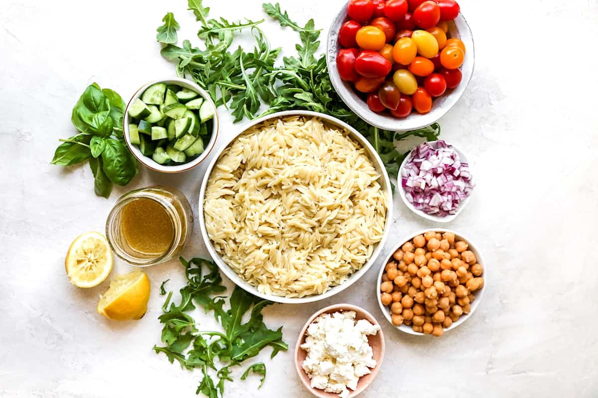 orzo salad ingredients in bowls. 