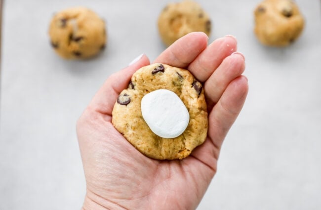 s'mores cookie dough in hand with a marshmallow center.