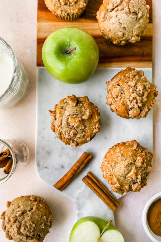 Apple Cinnamon Muffins with crumb topping on board with apple.