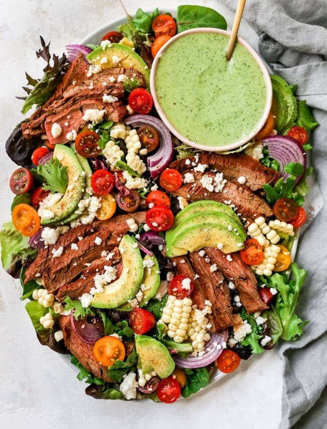 steak salad on platter with dressing