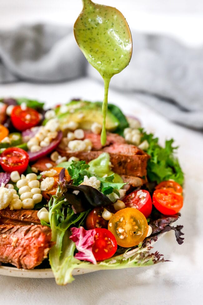 Drizzling dressing over steak salad