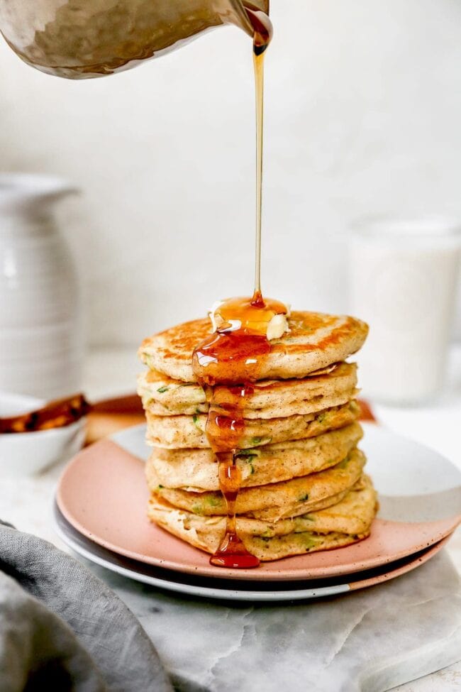 stack of zucchini pancakes with butter and maple syrup 