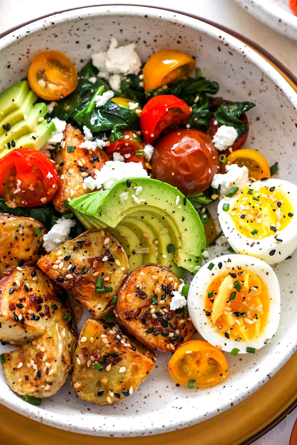 Savory Breakfast Bowl with potatoes, eggs, avocado, tomatoes, and spinach.
