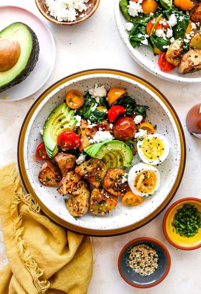 Healthy Savory Breakfast Bowl with eggs, potatoes, avocado, tomatoes, spinach, and cheese