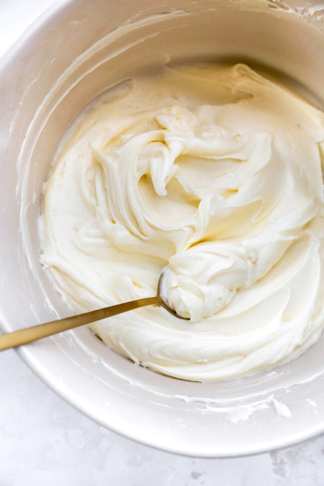 cream cheese frosting in a bowl with a spoon.