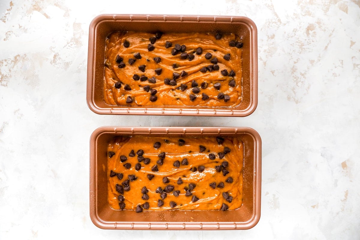 pumpkin chocolate chip bread batter in two loaf pans. 