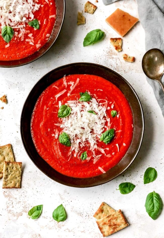 Roasted Tomato Basil Soup in a bowl with Parmesan cheese and basil