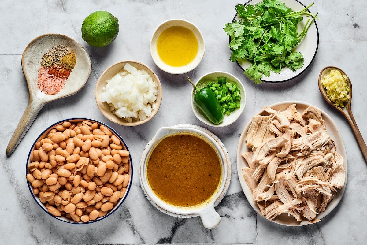 This comforting white chicken chili is easy to make with white beans, zesty seasonings, and rotisserie chicken. A favorite weeknight meal! The ingredients for homemade white chicken chili.