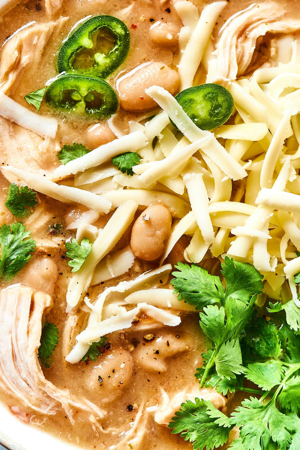 Close up of white chicken chili garnished with fresh cilantro leaves.