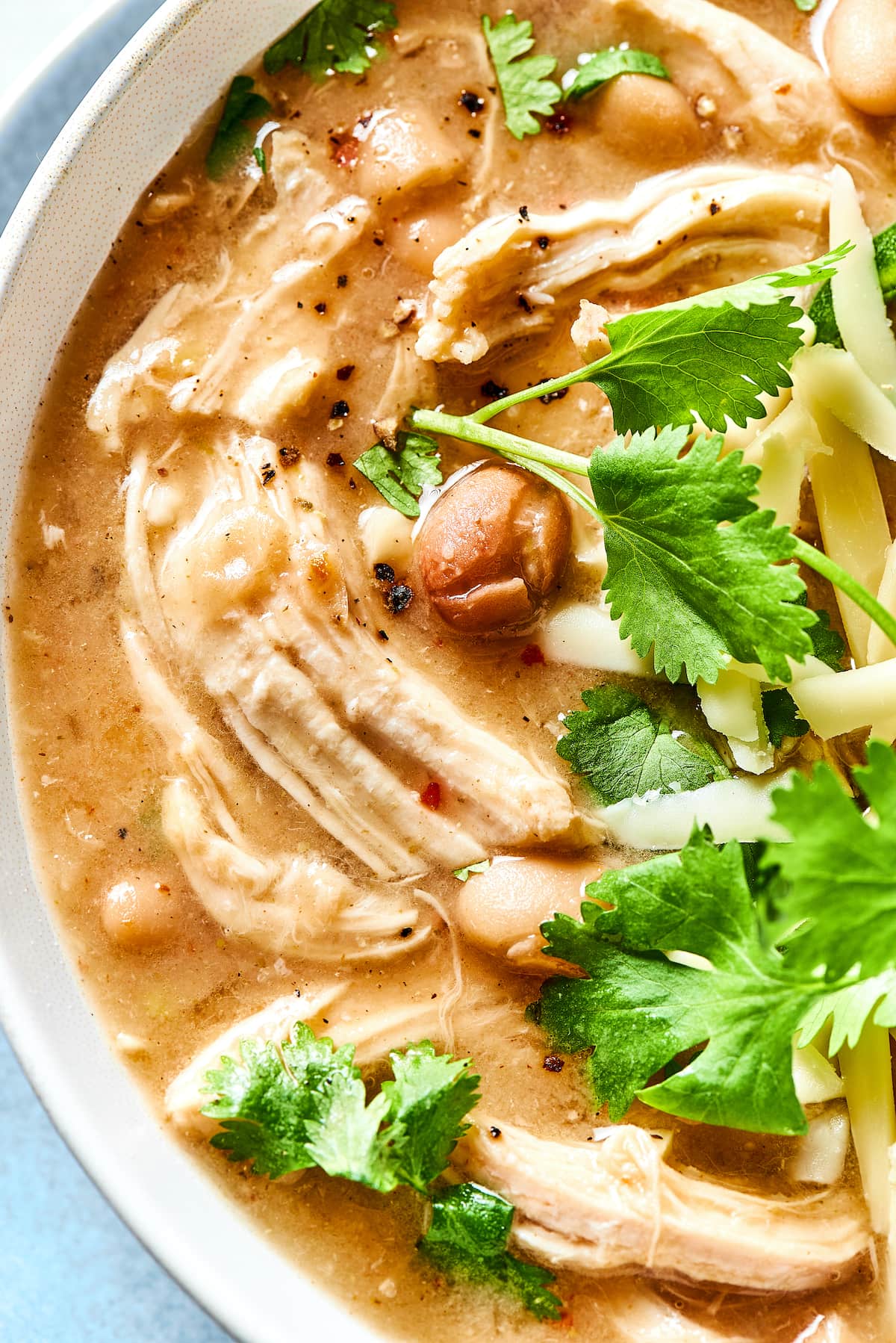 Close up of white chicken chili garnished with fresh cilantro leaves.