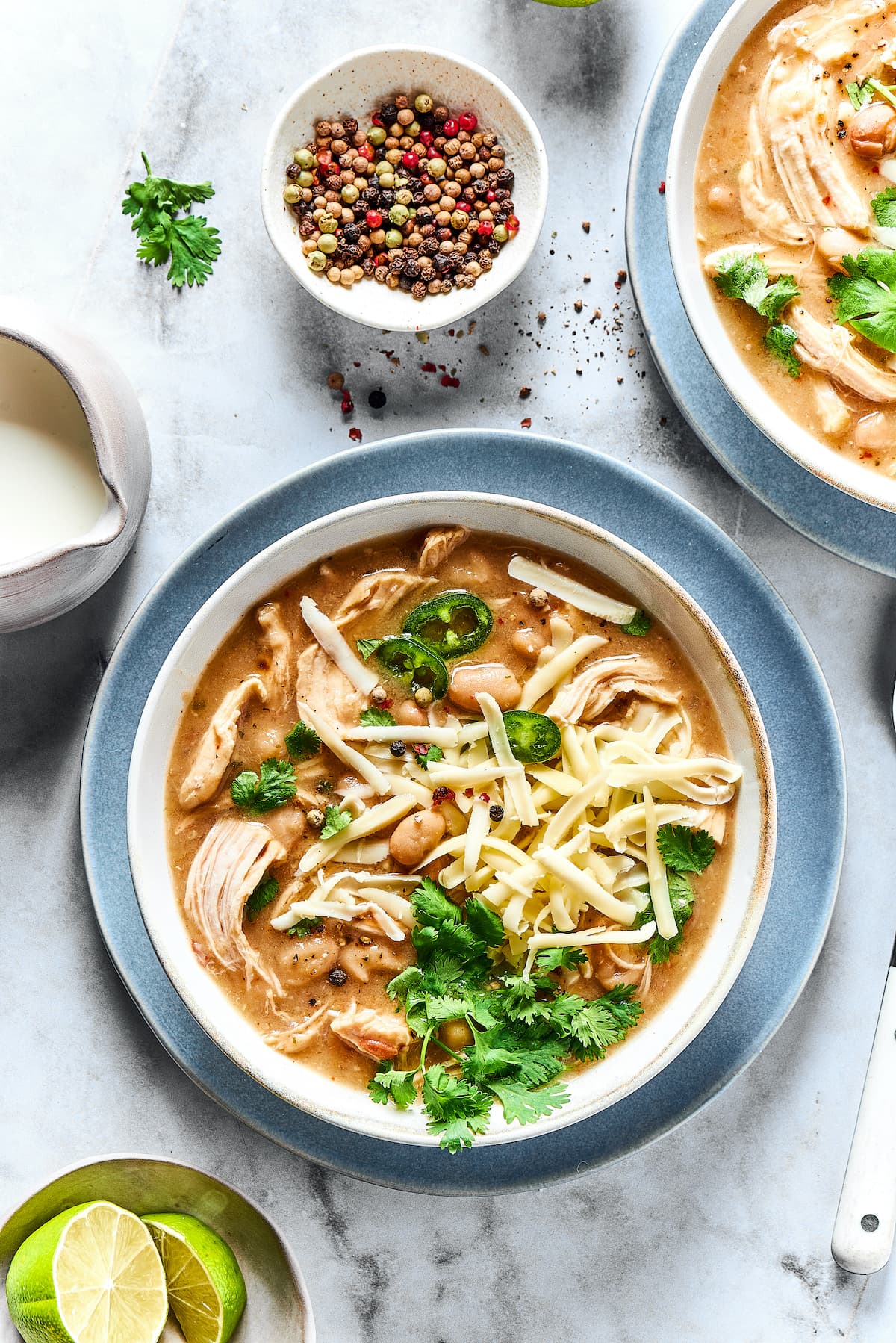 A bowl of white chicken chili surrounded by chili toppings.