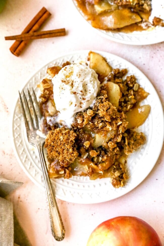 Apple Crumble with a scoop of vanilla ice cream on plate with a fork. 