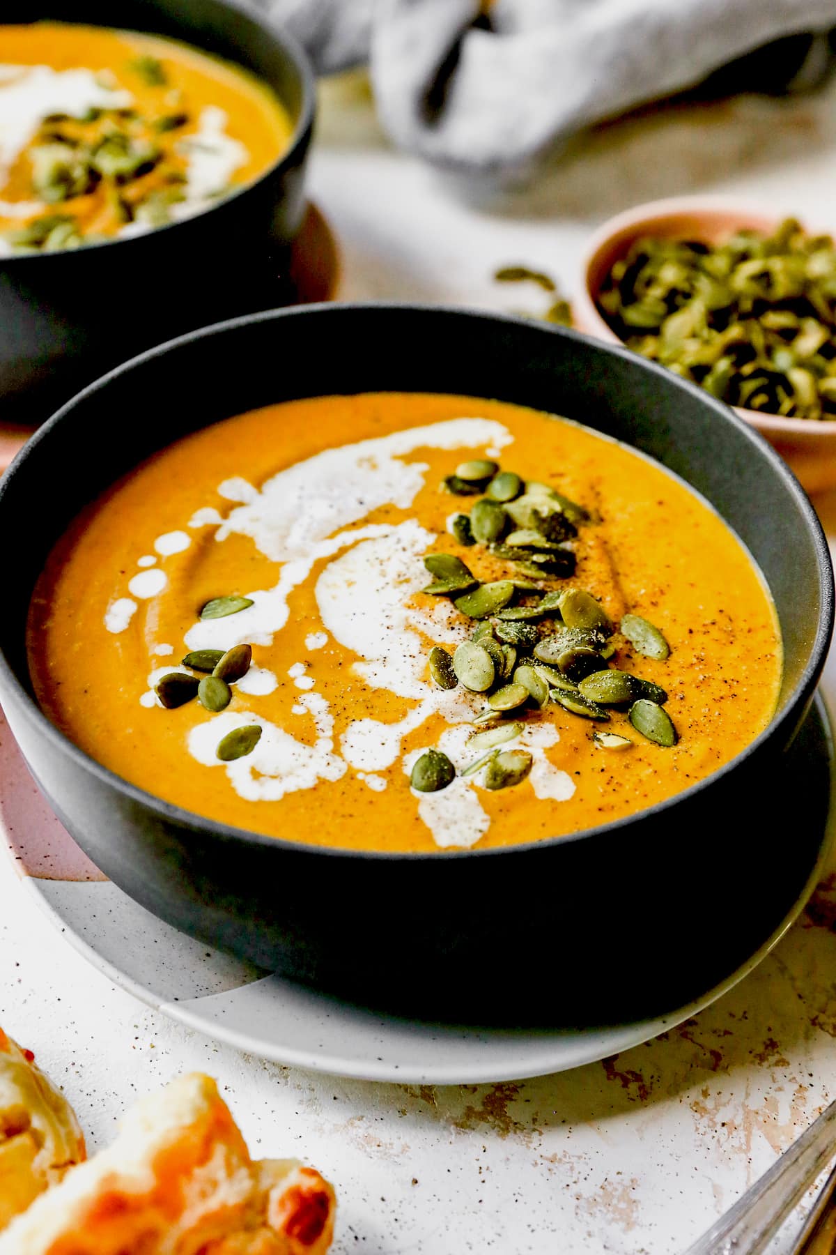 pumpkin soup in bowl with pepitas and cream.