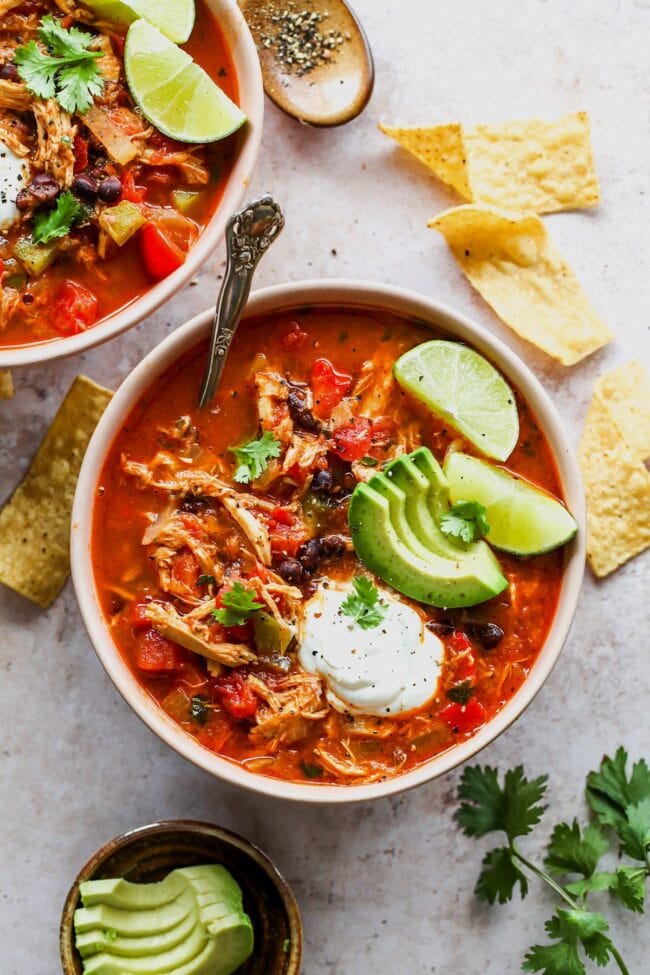 Chicken Fajita Soup in bowl with avocado, lime, and sour cream