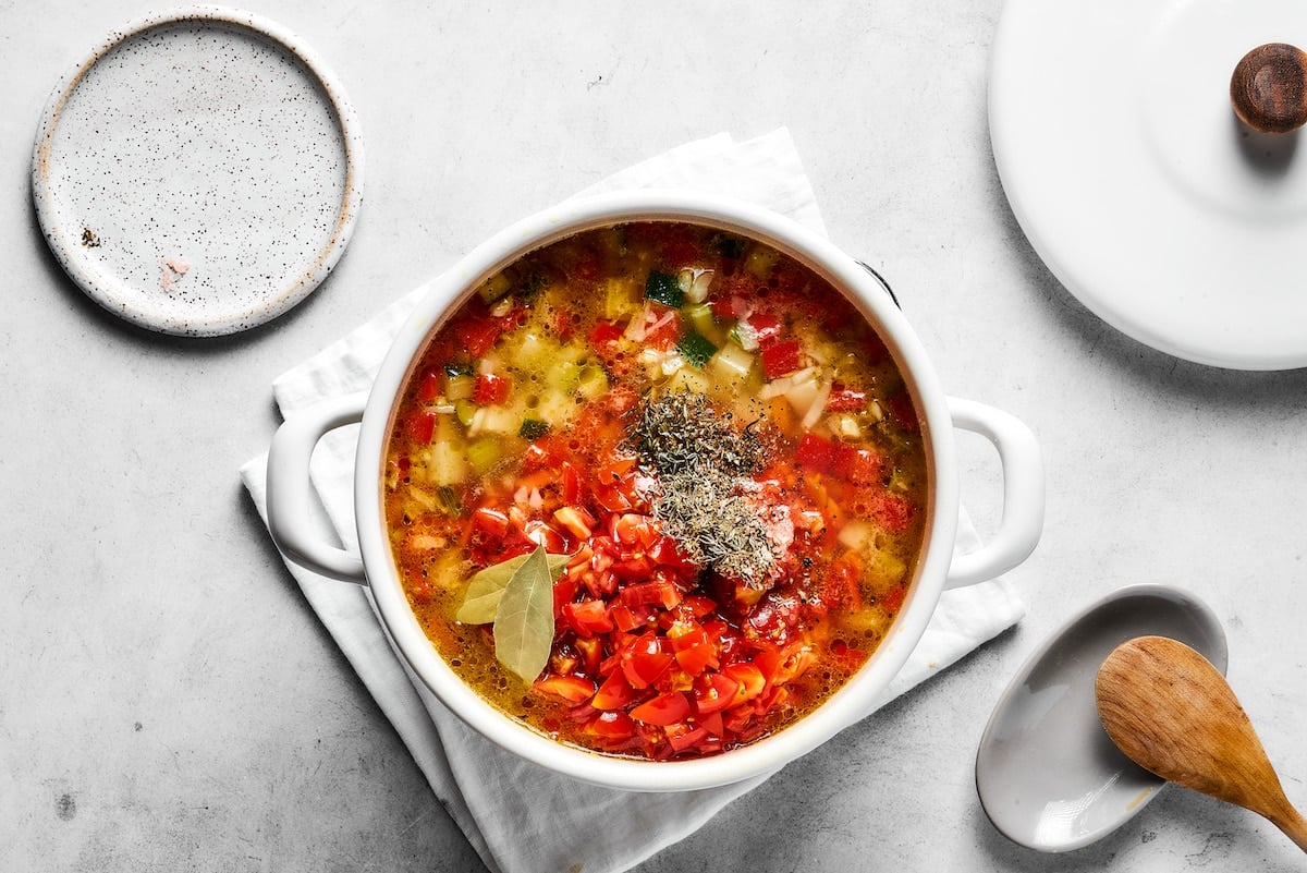 Vegetable soup ingredients combined in a saucepan.