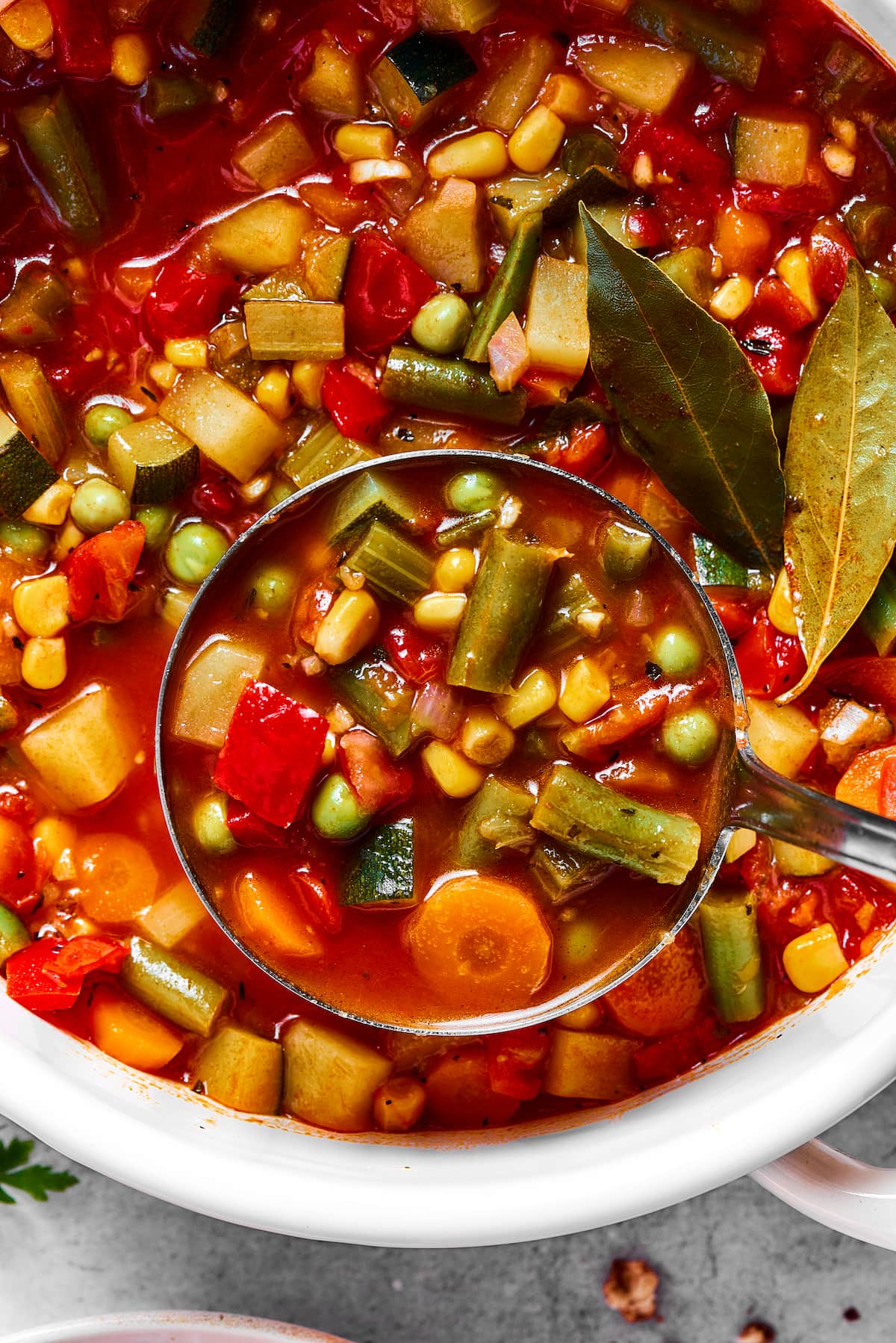 Close up of vegetable soup being ladled from a pot.