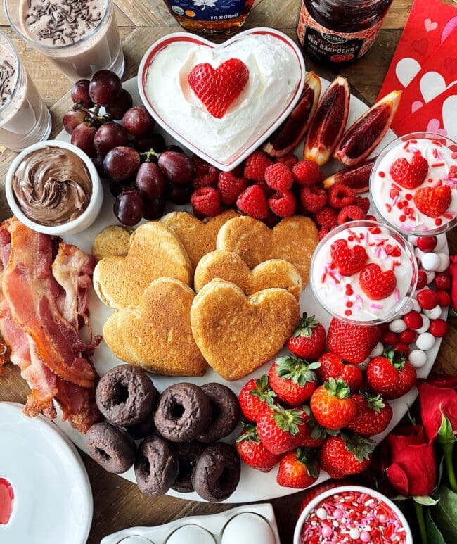 breakfast board with heart pancakes, fruit, and donuts