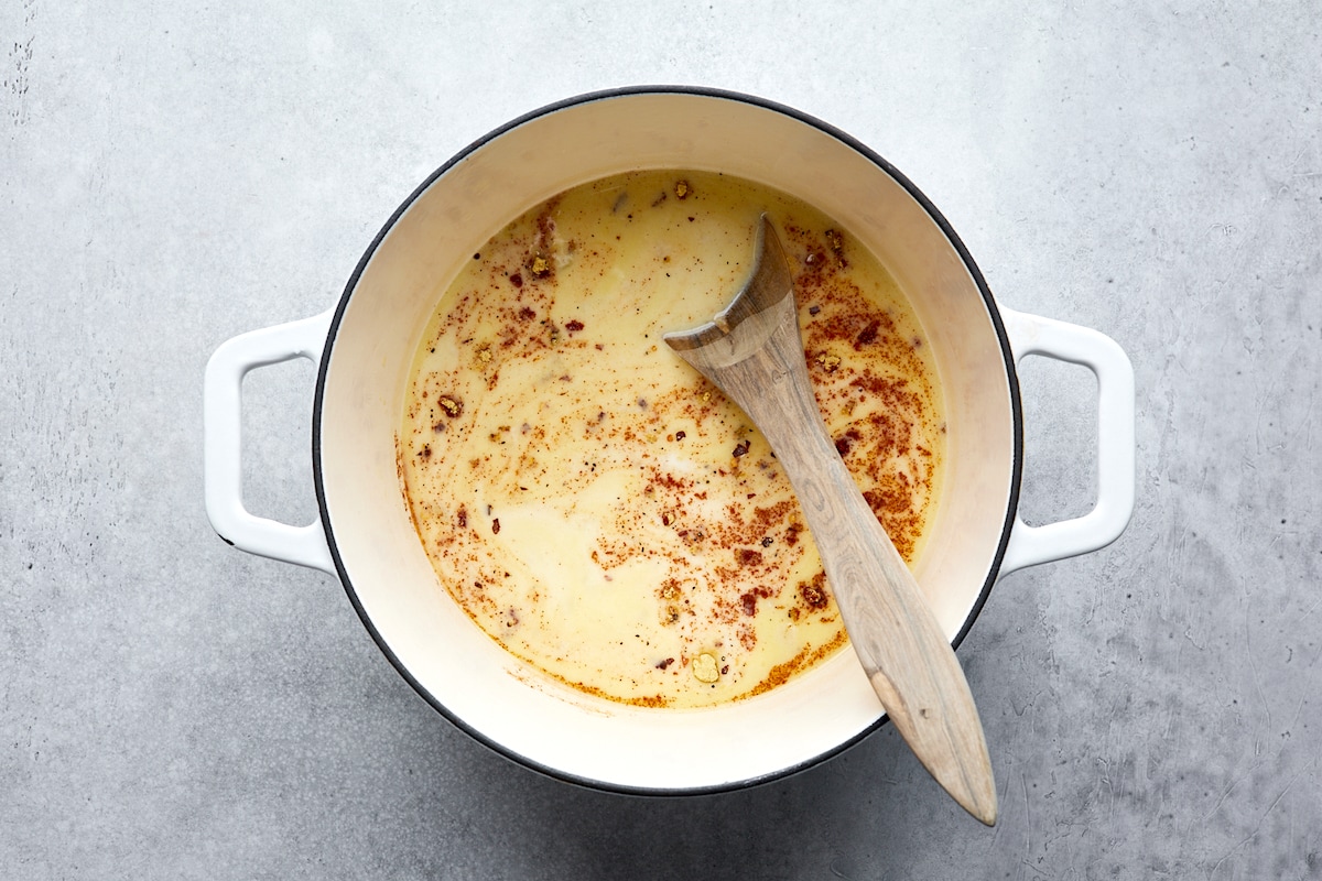 making broccoli cheese soup in pot with wooden spoon. 