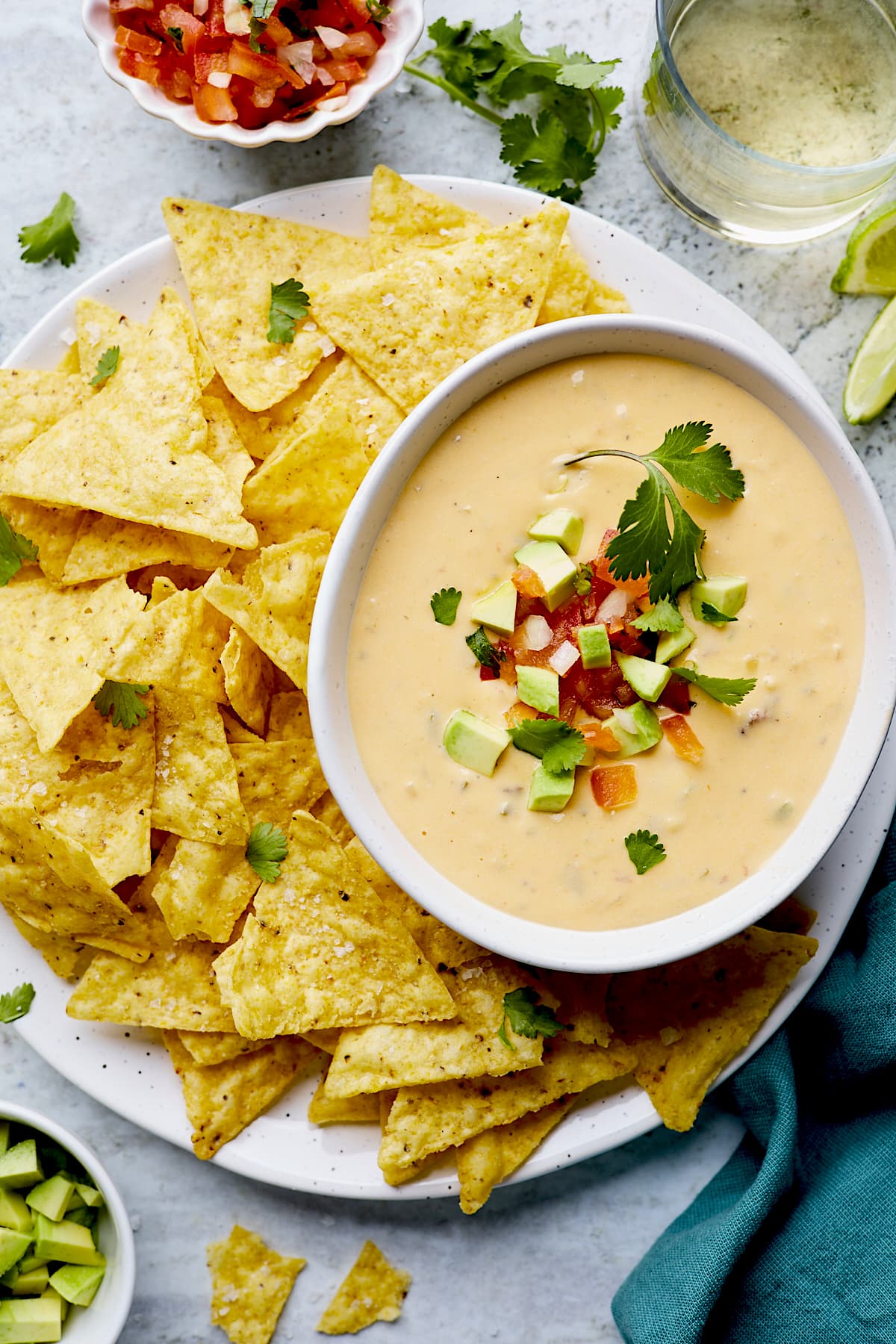 Queso in a bowl on platter with tortilla chips. 