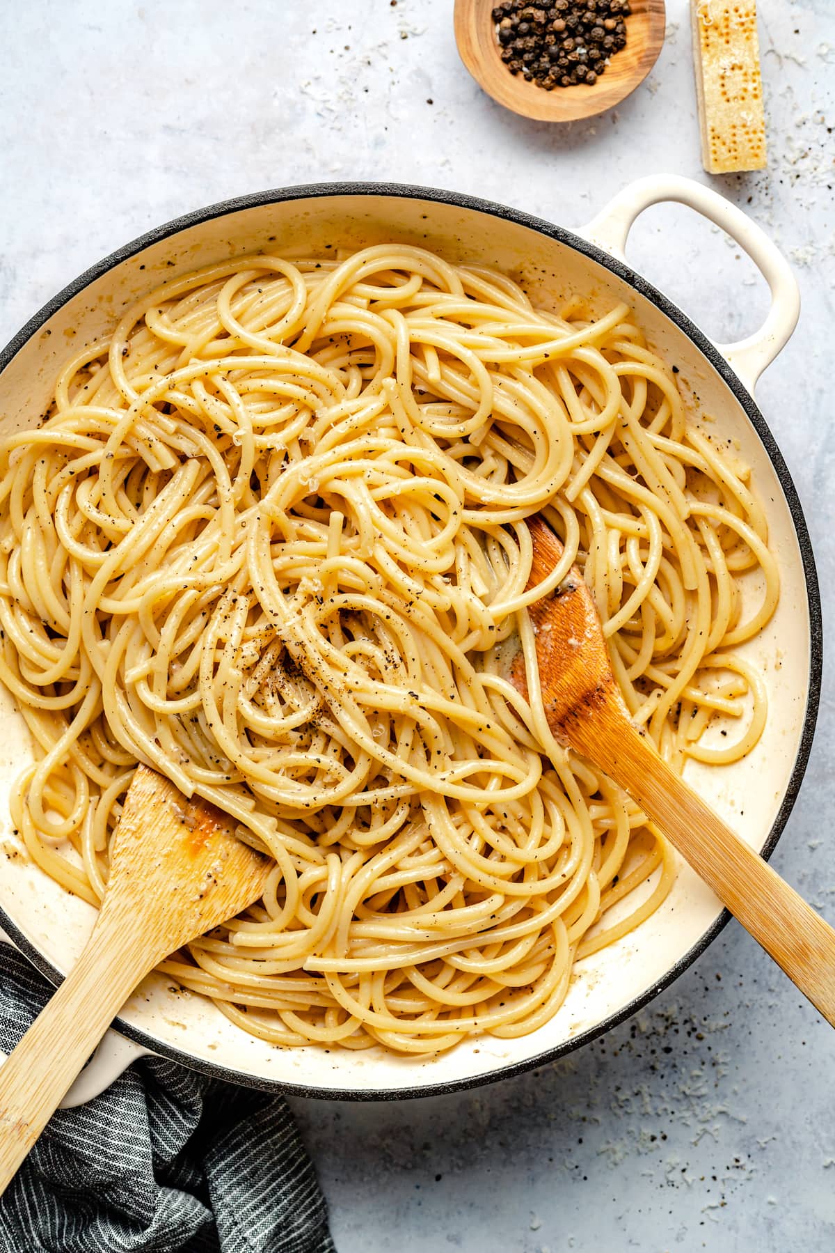 Cacio e Pepe in pan with wooden serving spoons. 