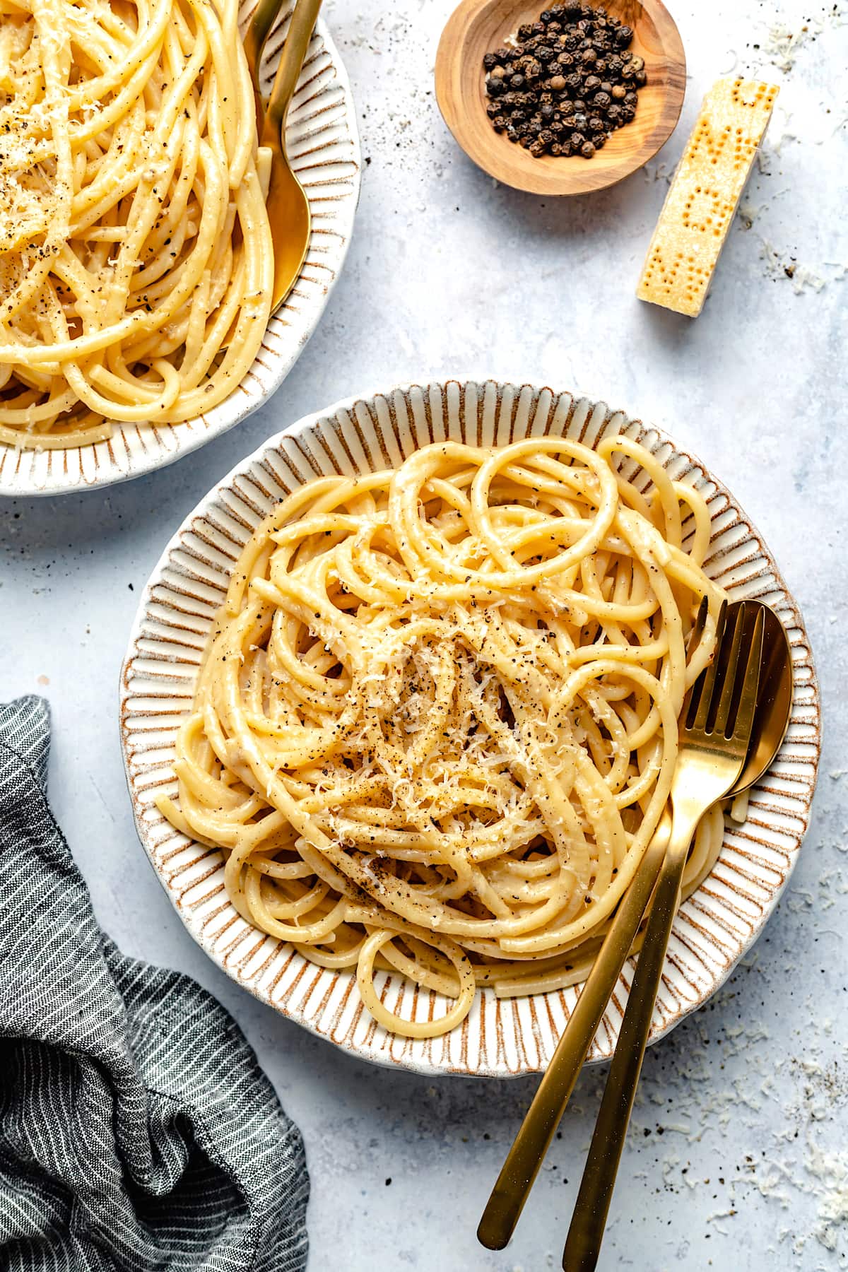 Cacio e Pepe on plate with gold silverware. 