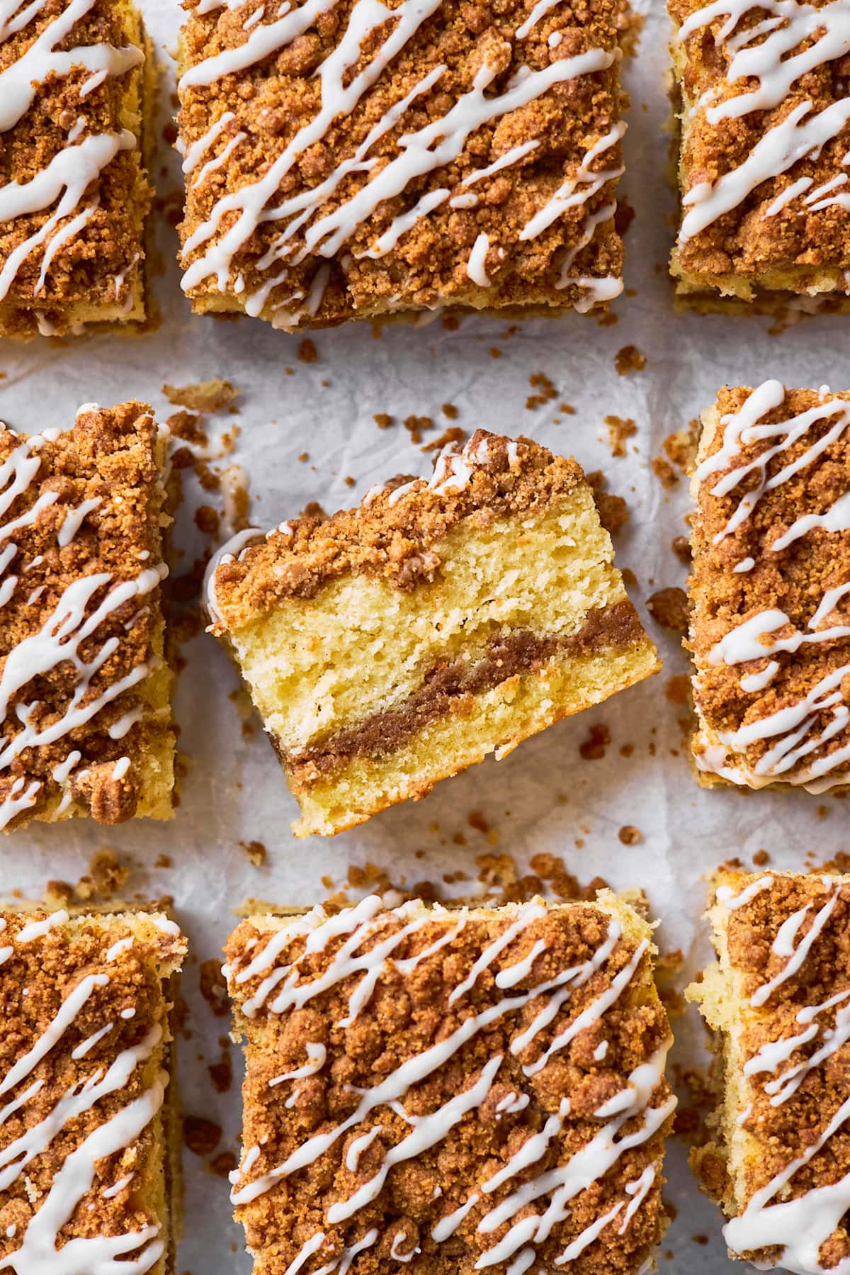 pieces of coffee cake with streusel and vanilla glaze on parchment paper.