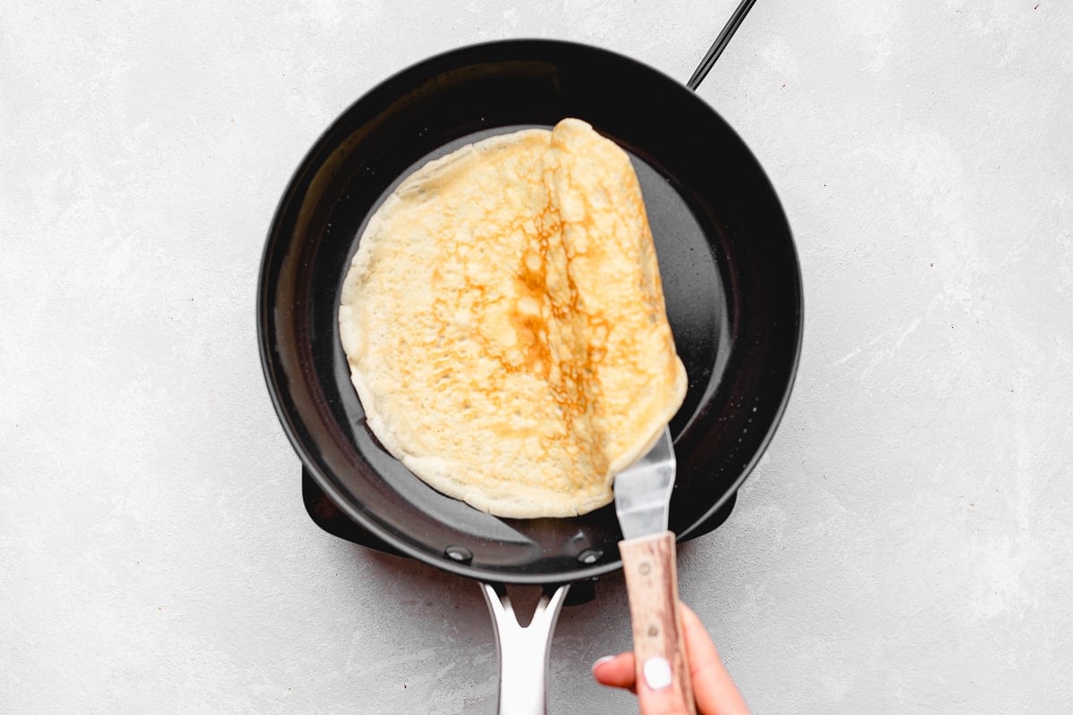 flipping crepe in skillet with a spatula. 