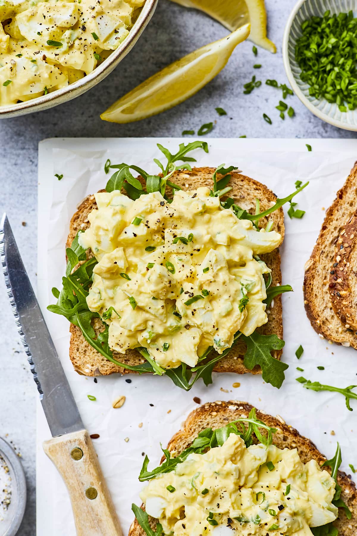 egg salad on slices of bread with arugula. 