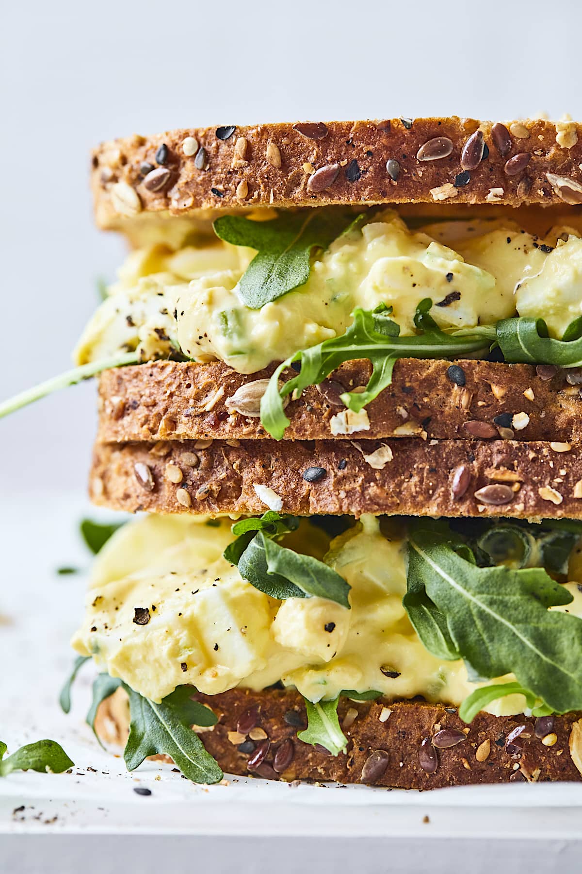 close up of 2 egg salad sandwiches stacked on top of each other. 