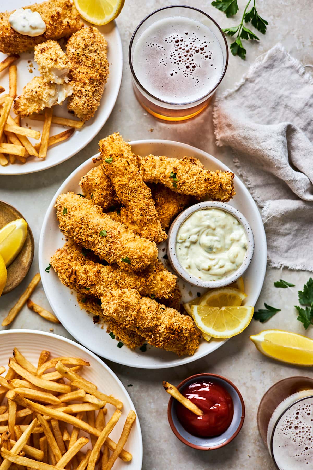 fish sticks on plate with small bowl of tartar sauce and lemon slices. 