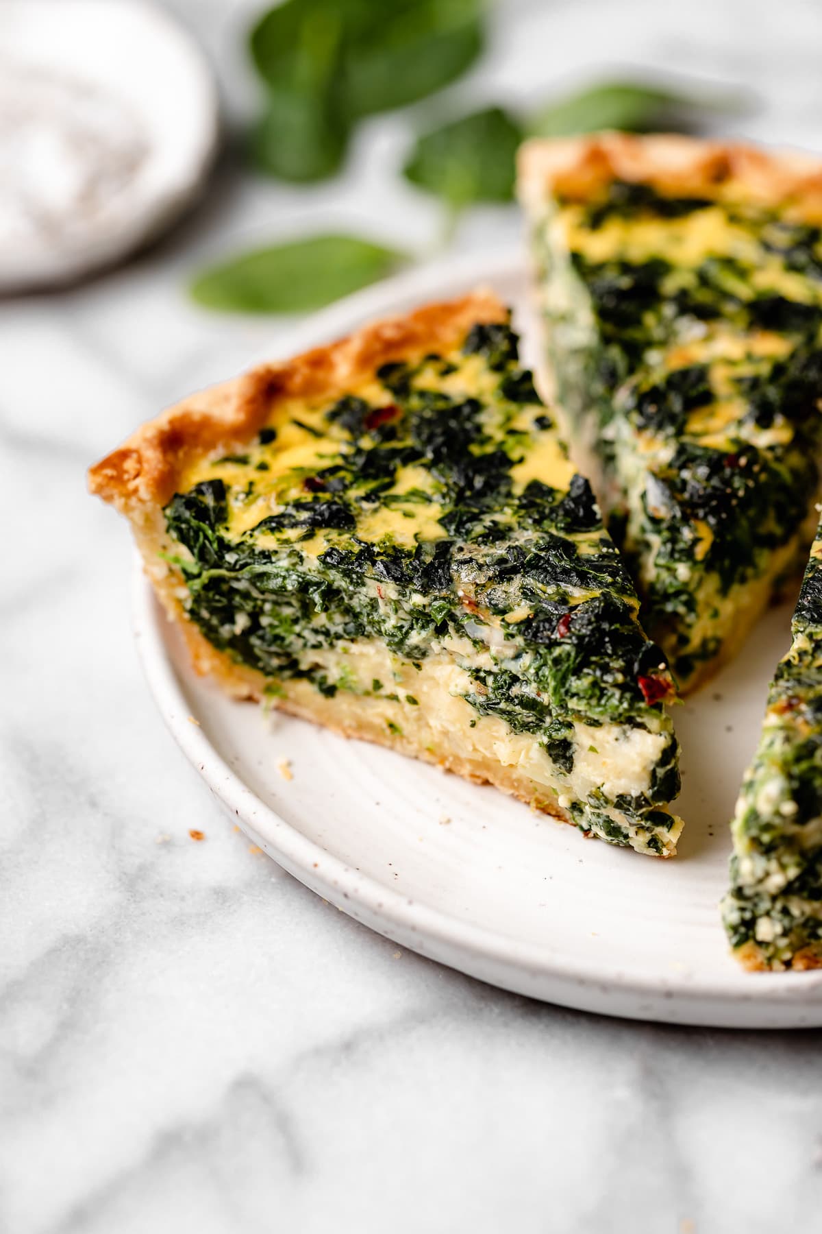 spinach quiche cut into pieces on plate.