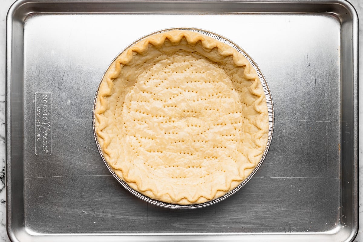 pie crust in pan on baking sheet with fork pricks on the bottom. 